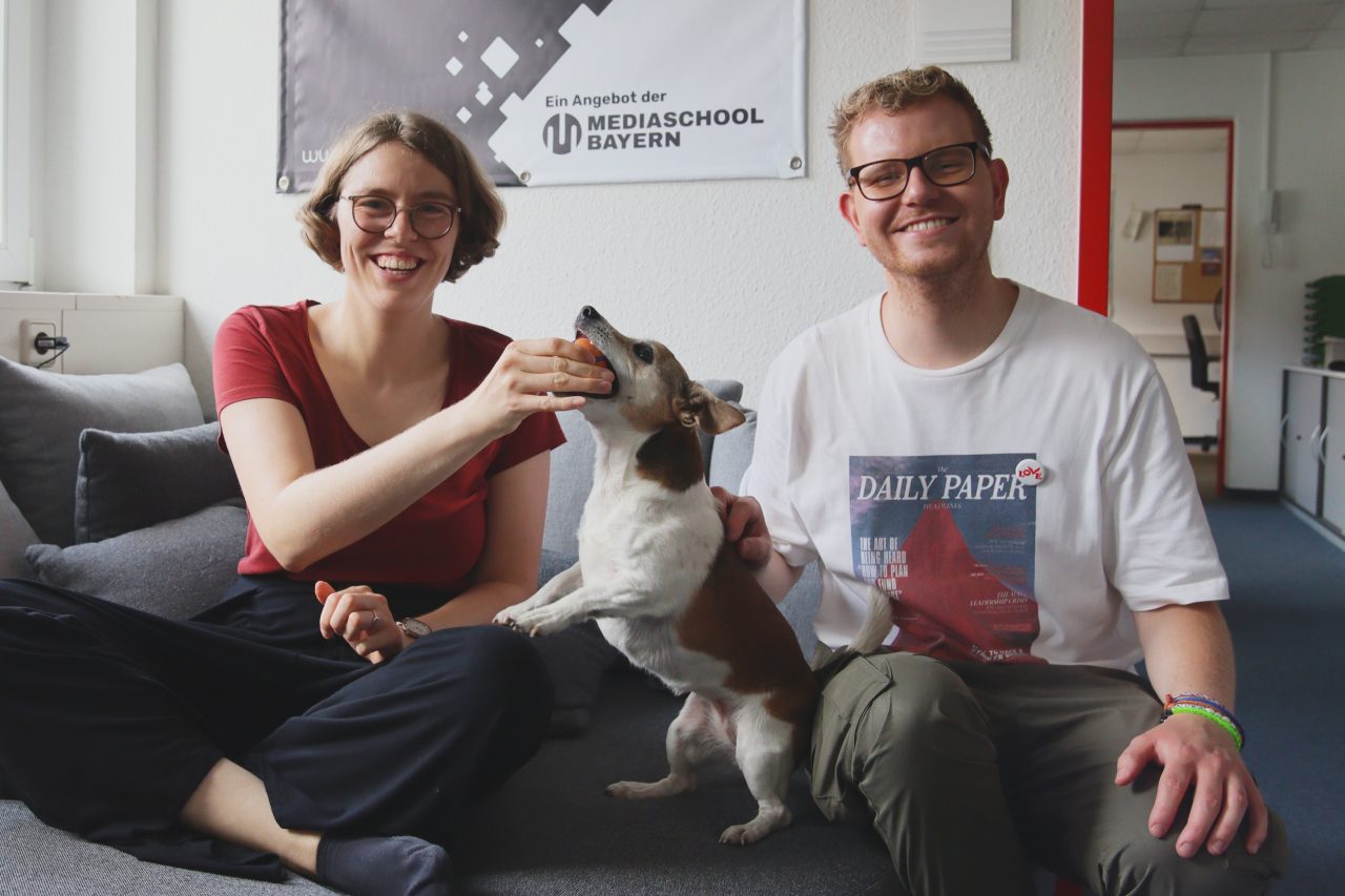 Das Foto zeigt den Musiker Ferdinand Schwartz mit Moderatorin Lena Schnelle und Redaktionshündin Floppy. Die drei sitzen auf dem Sofa.