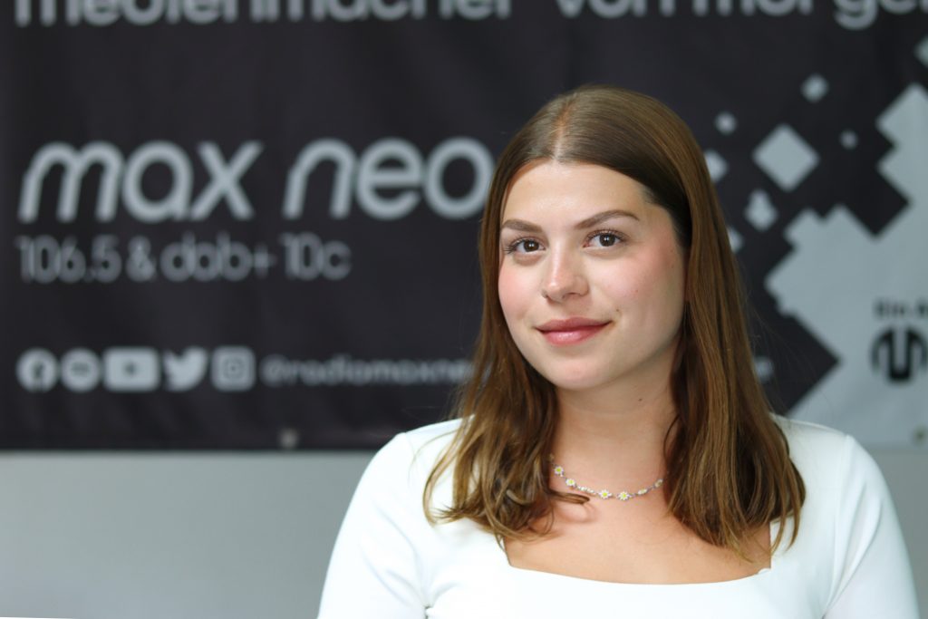 Das Foto zeigt Sarah Kürzdörfer im Porträt vor dem max neo Banner.