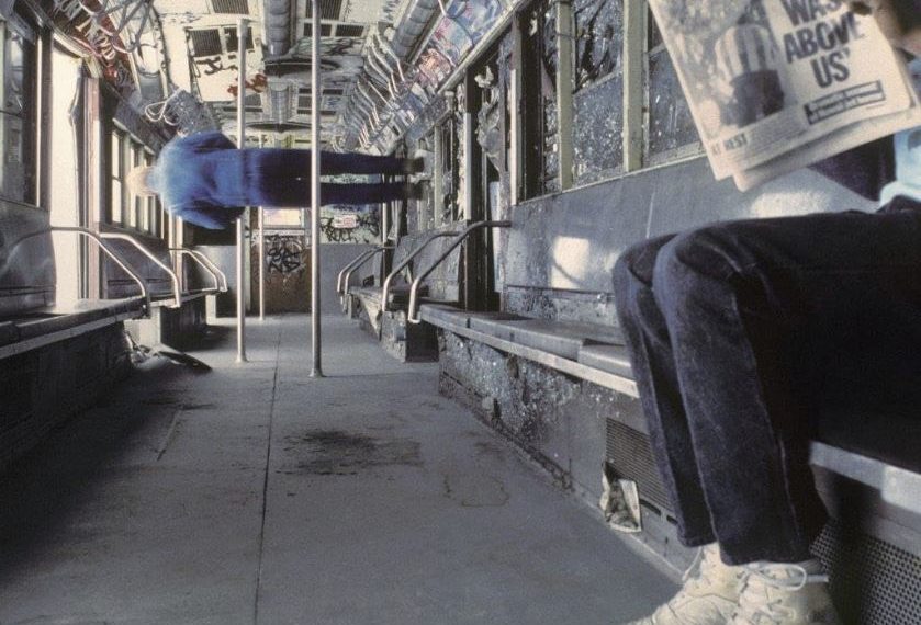 Das Albumcover "Only God Was Above Us" von Vampire Weekend zeigt einen Mann in der U-Bahn, der eine Zeitung mit dem Titel "Only God Was Above Us" liest. Weiter hinten steht ein Mann seitwärts in der U-Bahn.