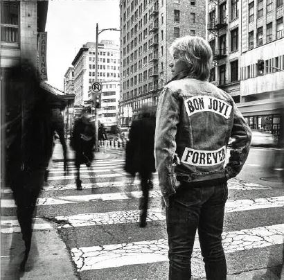 Das Albumcover "Forever" von Bon Jovi zeigt den Musiker von hinten, wie er auf dem Zebrastreifen einer Stadt steht, Auf seiner Jacke stehen sein Name und der Albumtitel. Das Bild ist schwarz-weiß.