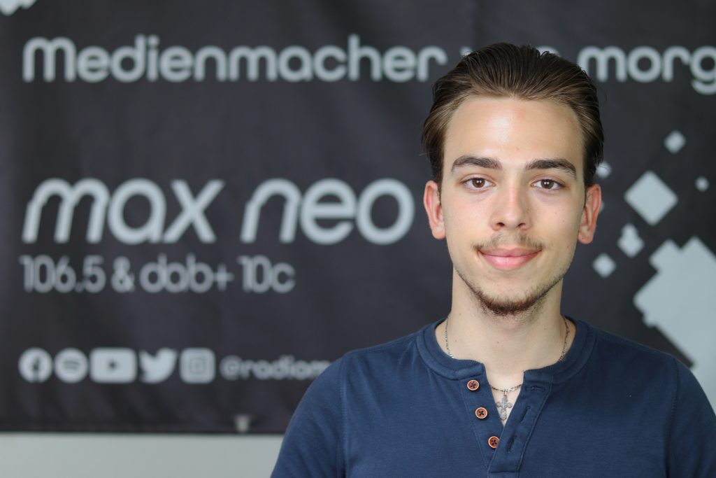 Das Foto zeigt Artjom Lorenz im Porträt vor dem max neo Banner.