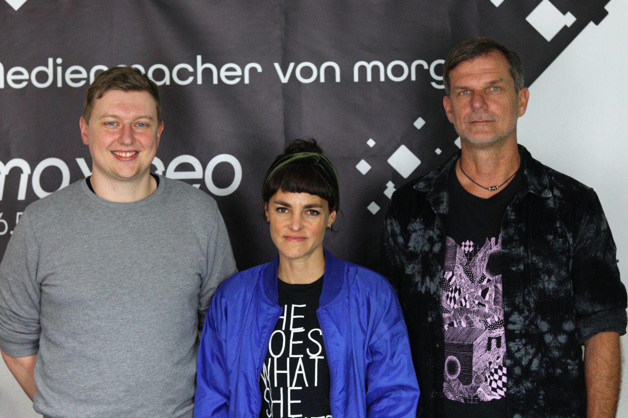 Das Foto zeigt Nora und Michael von der Band Apanorama mit Moderator Moritz Bayer.