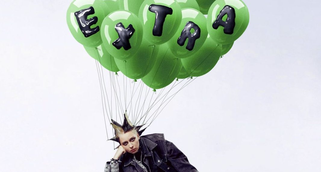 Das Albumcover "Extra" von Paula Carolina zeigt die Musikerin auf dem Boden sitzend. An ihren Haaren hänge grüne Luftballons.