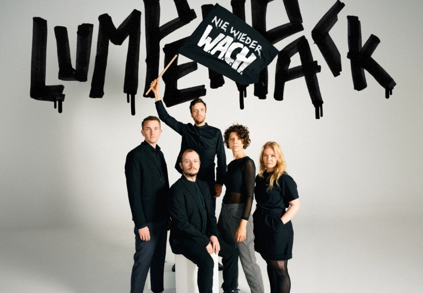 Das Albumcover "Nie wieder W.A.C.H." vom Lumpenpack zeigt die Band in schwarz. Sie schwenken eine Fahne mit dem Albumtitel. Im Hintergrund steht der Bandname.