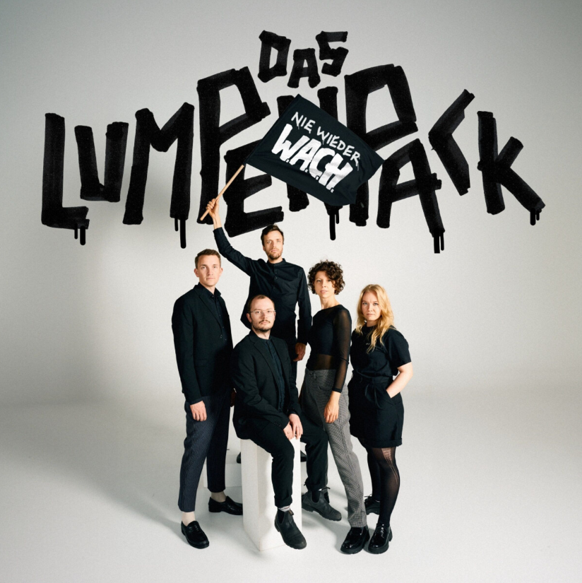 Das Albumcover "Nie wieder W.A.C.H." vom Lumpenpack zeigt die Band in schwarz. Sie schwenken eine Fahne mit dem Albumtitel. Im Hintergrund steht der Bandname.